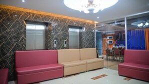 A lobby with a red and beige sofa, elevators, and a chandelier. - Hotel Victory Abashik Cumilla (Comilla)