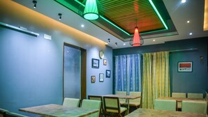 A dining area with tables and chairs, a clock on the wall, and a door. - Hotel Victory Abashik Cumilla (Comilla)