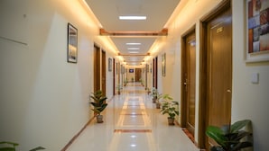 A hotel corridor with a polished floor, wooden doors, and potted plants. - Hotel Victory Abashik Cumilla (Comilla)