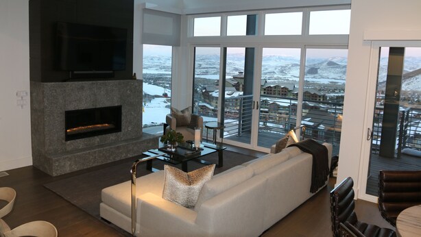 A modern living room with a fireplace, a sofa, and a large window offering a view of a snowy landscape.