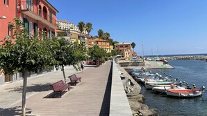 A coastal promenade with a row of colorful buildings, a paved walkway, and boats docked at the pier. - Beautiful apartment for 5 guests with WIFI, TV, balcony and pets allowed (Imperia)