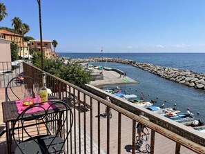 A seaside terrace with a table set for dining, overlooking a rocky harbor with boats and a clear view of the sea. - Beautiful apartment for 5 guests with WIFI, TV, balcony and pets allowed (Imperia)