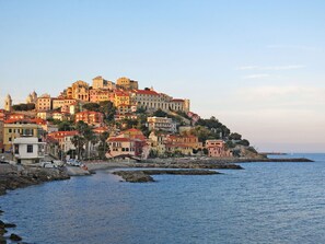 Un pueblo costero con edificios históricos, un puerto deportivo y un litoral rocoso.