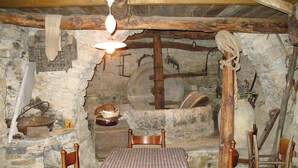 A rustic stone-walled room with a wooden table and chairs, a hanging light fixture, and stone walls. - Beautiful private villa with A/C, private pool, WIFI, TV, patio, pets allowed and panoramic view (Borgomaro)