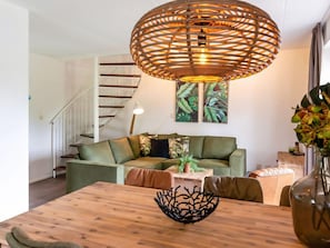 Una sala moderna con una mesa de comedor de madera, un sofá verde y una escalera.