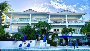 Un hotel de varios pisos con piscina, balcones y sillas de descanso.