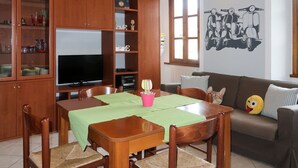 Una sala de estar con un aparador de madera, televisor, mesa de comedor con sillas y un sofá.