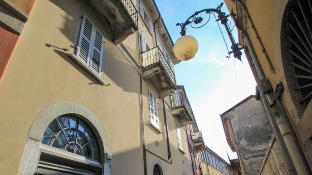 Una calle estrecha con edificios que tienen ventanas abovedadas y balcones.