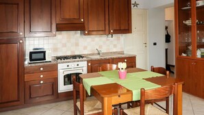 Una cocina con armarios de madera, microondas, estufa y una mesa de comedor con sillas.