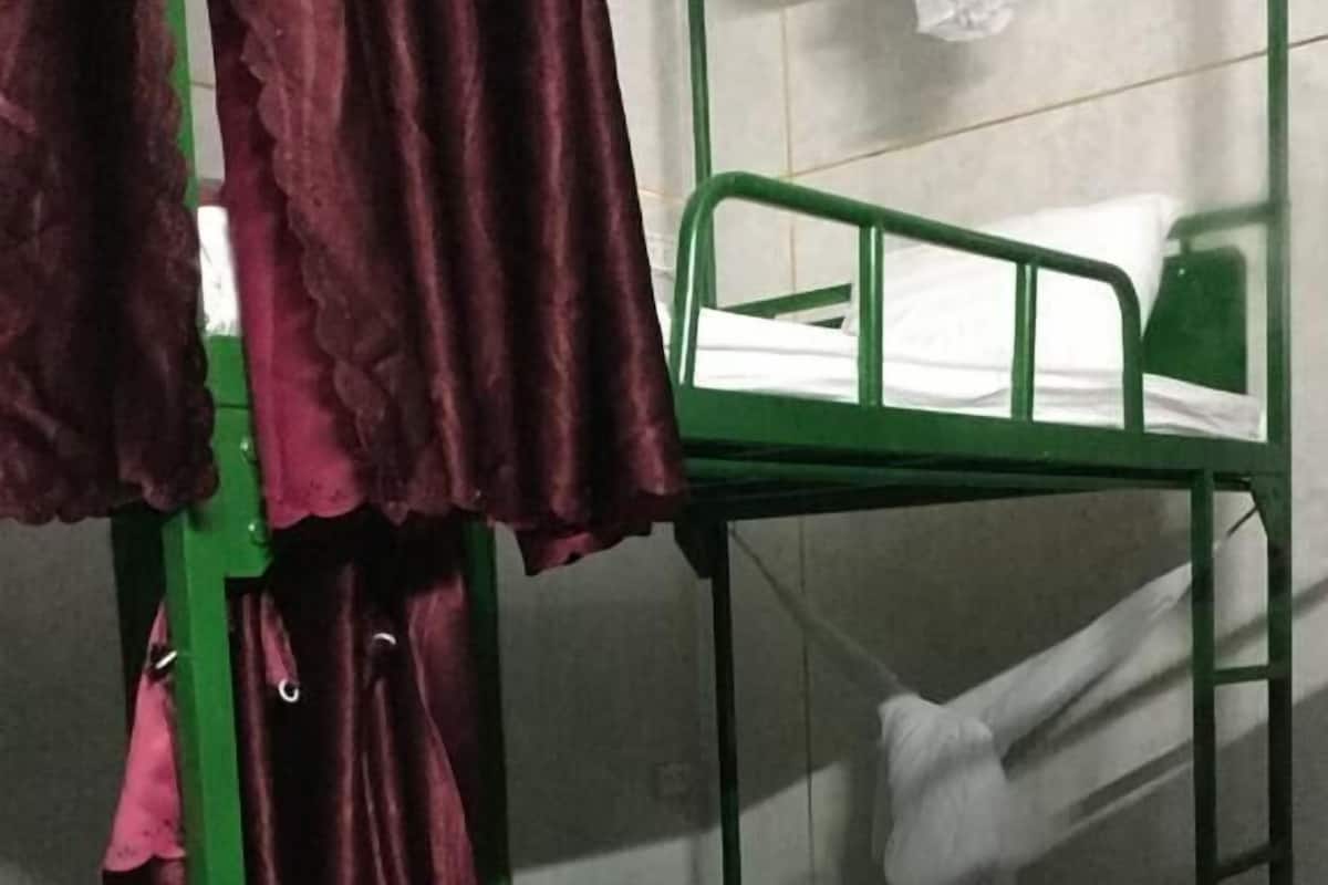 A bunk bed with a green frame and white bedding.