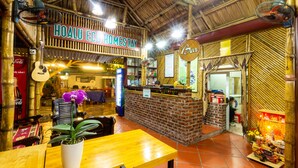 A restaurant with a bamboo interior, a sign reading "HOALU ECO HOMESTAY", and a bar area. - Hoa Lu Eco Homestay - Hostel (Tay Hoa Lu)