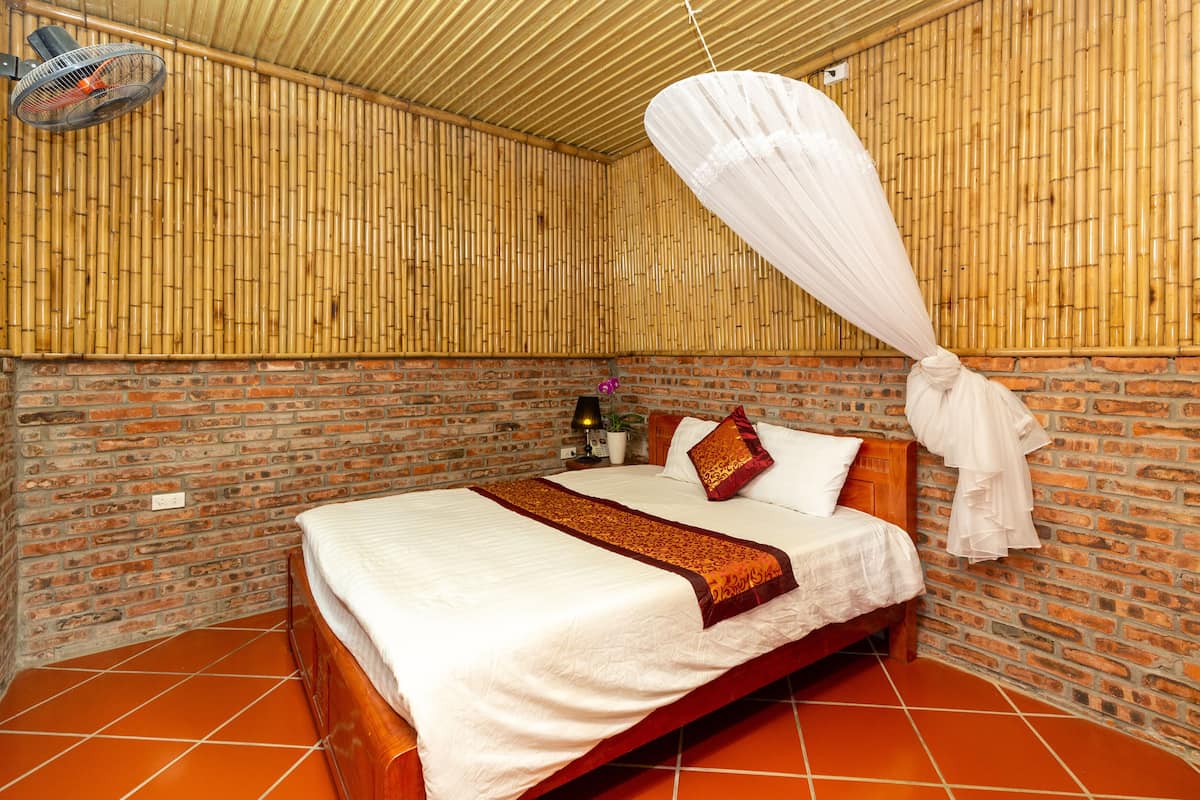 A room with a bed, a fan, and a bamboo wall.