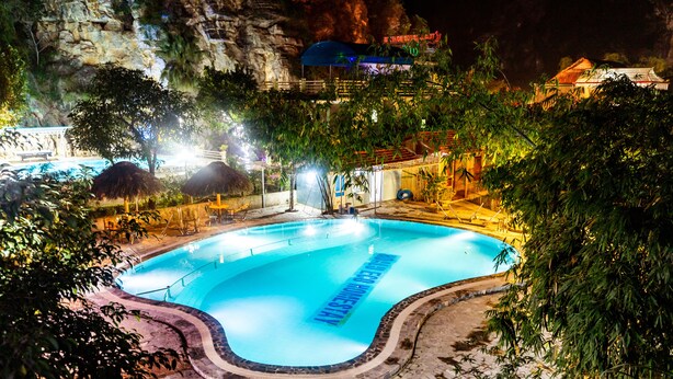 A swimming pool surrounded by trees and a stone wall. - Hoa Lu Eco Homestay - Hostel (Tay Hoa Lu)