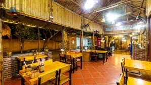 An indoor restaurant with bamboo walls, brick accents, and wooden tables and chairs. - Hoa Lu Eco Homestay - Hostel (Tay Hoa Lu)