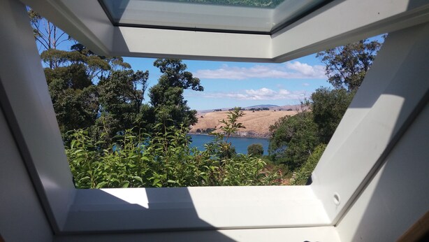 Um claraboia com vista para um lago rodeado por árvores e colinas.