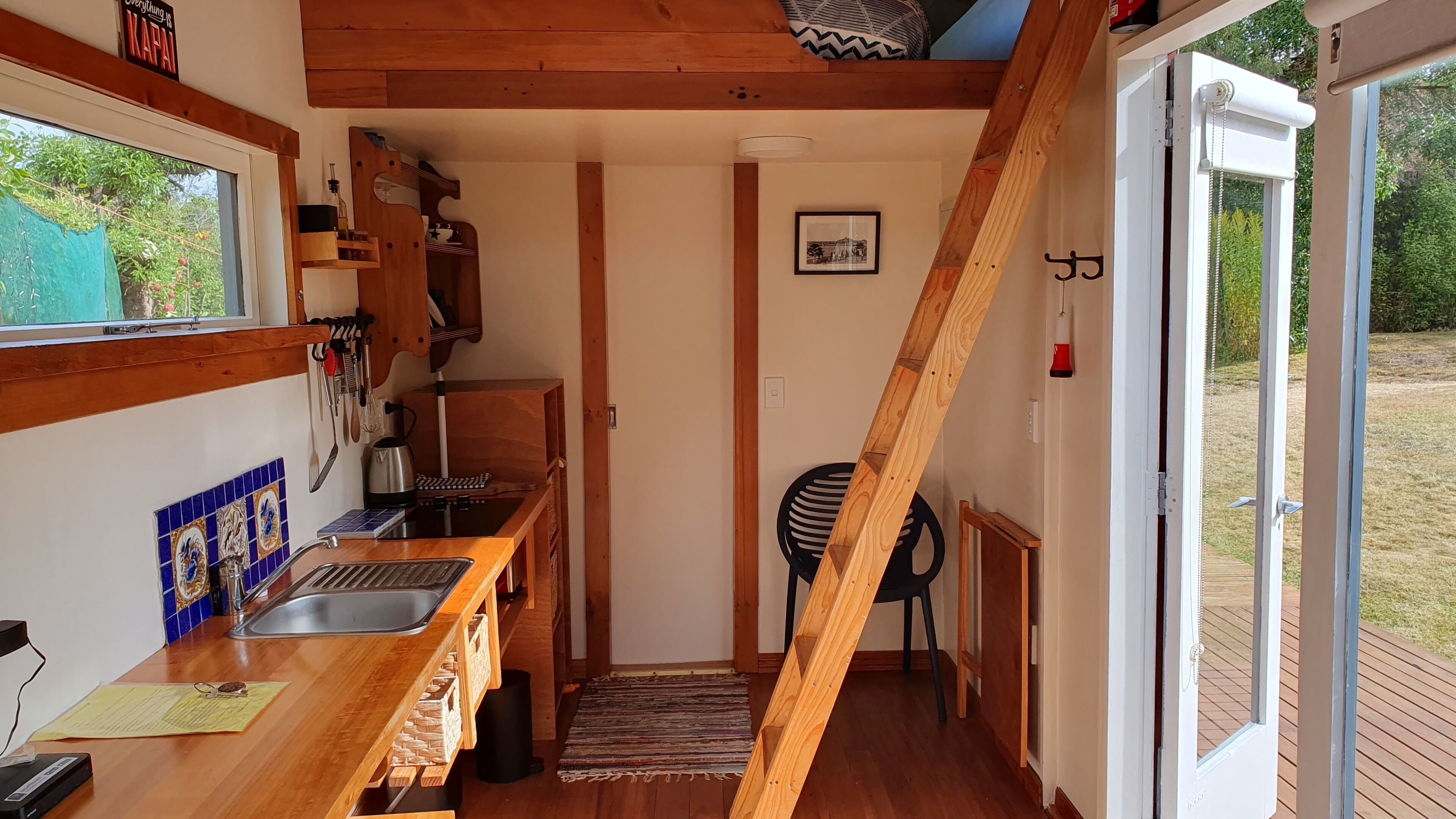 A compact kitchen with a wooden countertop, a sink, and a window overlooking a garden.