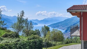A mountain view with a lake, a red building with a balcony, and lush greenery. - Beautiful private villa for 8 guests with WIFI, TV, terrace and pets allowed (Peglio)