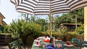 A green table with striped umbrellas, red patterned cups, and a kettle.