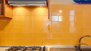 Cucina con gas, lavello e schienale rivestito di piastrelle gialle.