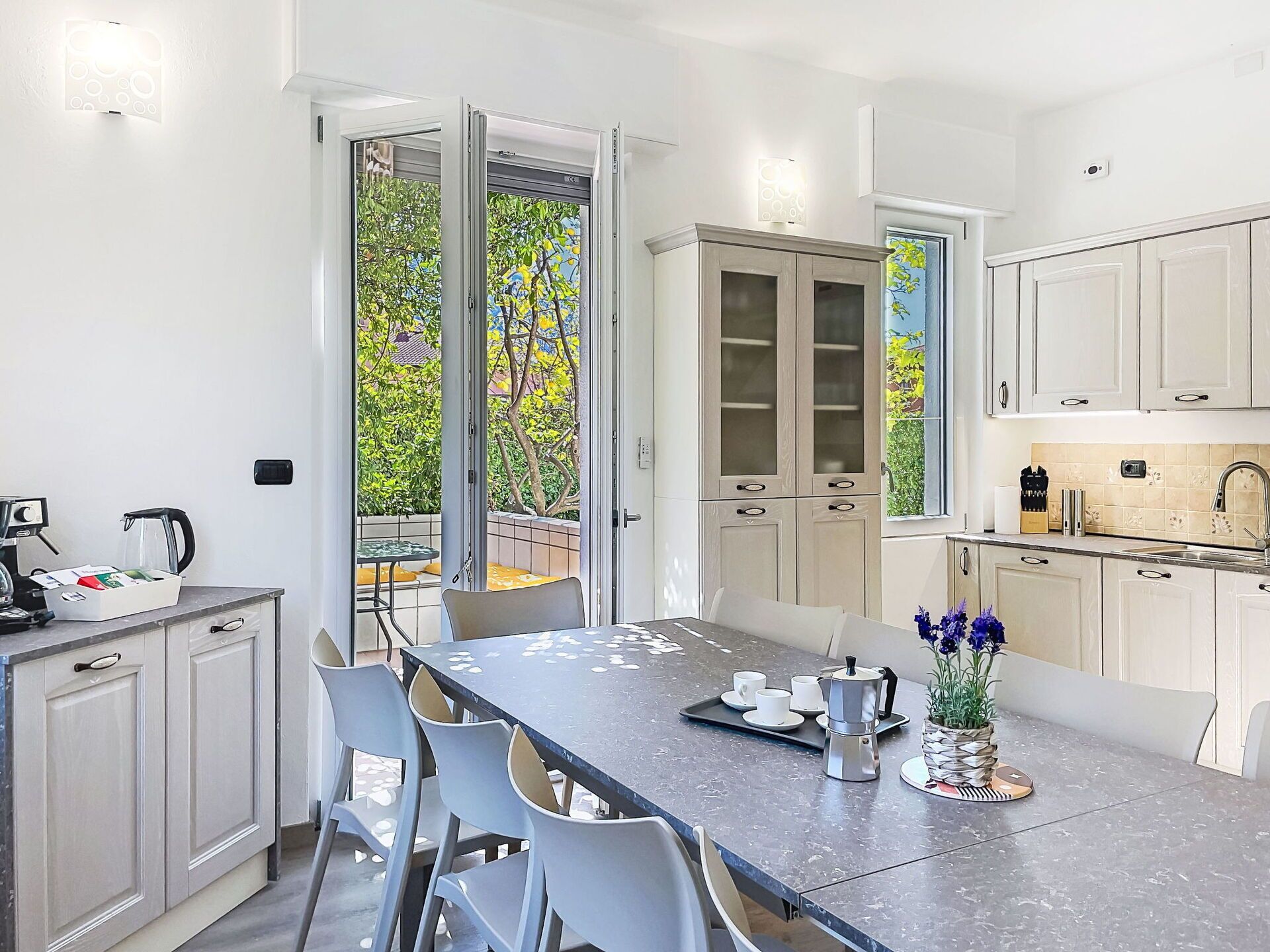 A modern kitchen with a dining area, featuring a coffee maker, cups, and a tray on the table.