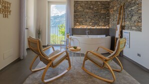 Ein modernes Badezimmer mit Steinwand, einer Badewanne und zwei Schaukelstühlen.