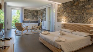Ein modernes Schlafzimmer mit Steinwand, einem Holzbett, einer Badewanne und einem Balkon mit Aussicht.