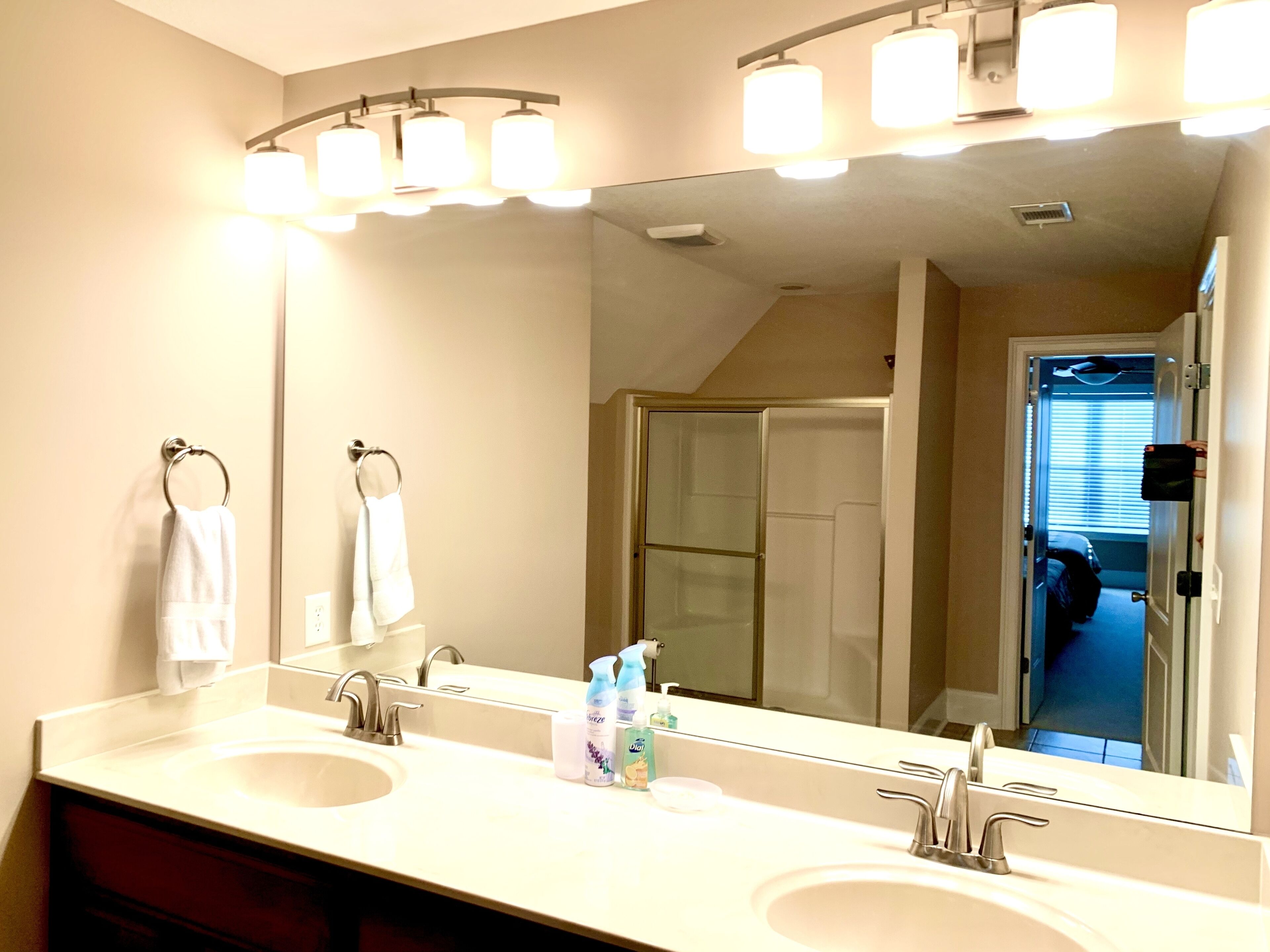 A bathroom with two sinks, a large mirror, and a shower area.