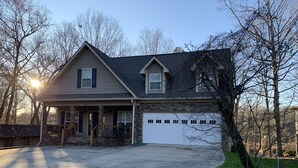 A two-story house with a stone foundation, a garage, and a front porch. - Lake Front Home. 3 Large Living Spaces. Screened Porches. Pet Friendly. (Lavonia)