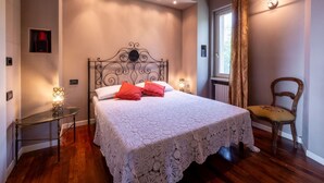 Une chambre à coucher avec un lit, une chaise, une petite table et une fenêtre.