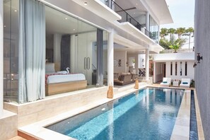 A modern hotel room with a large bed, a glass-enclosed bathroom, and a pool area with lounge chairs. - 🏖 Private room with pool, 5min walk to Echo Beach (Seminyak)