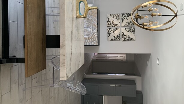 Een moderne keuken met marmeren aanrecht, een decoratief muurornament en een bijzondere lamp.