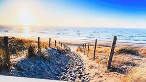 Una playa arenosa con una cerca de madera y una vista despejada del océano.