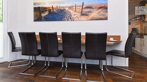 Un comedor con una mesa larga y cuatro sillas negras con patas cromadas.