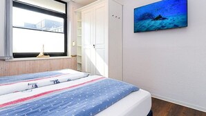 Et soveværelse med en seng, et vindue, et klædeskab og et billede på væggen.
