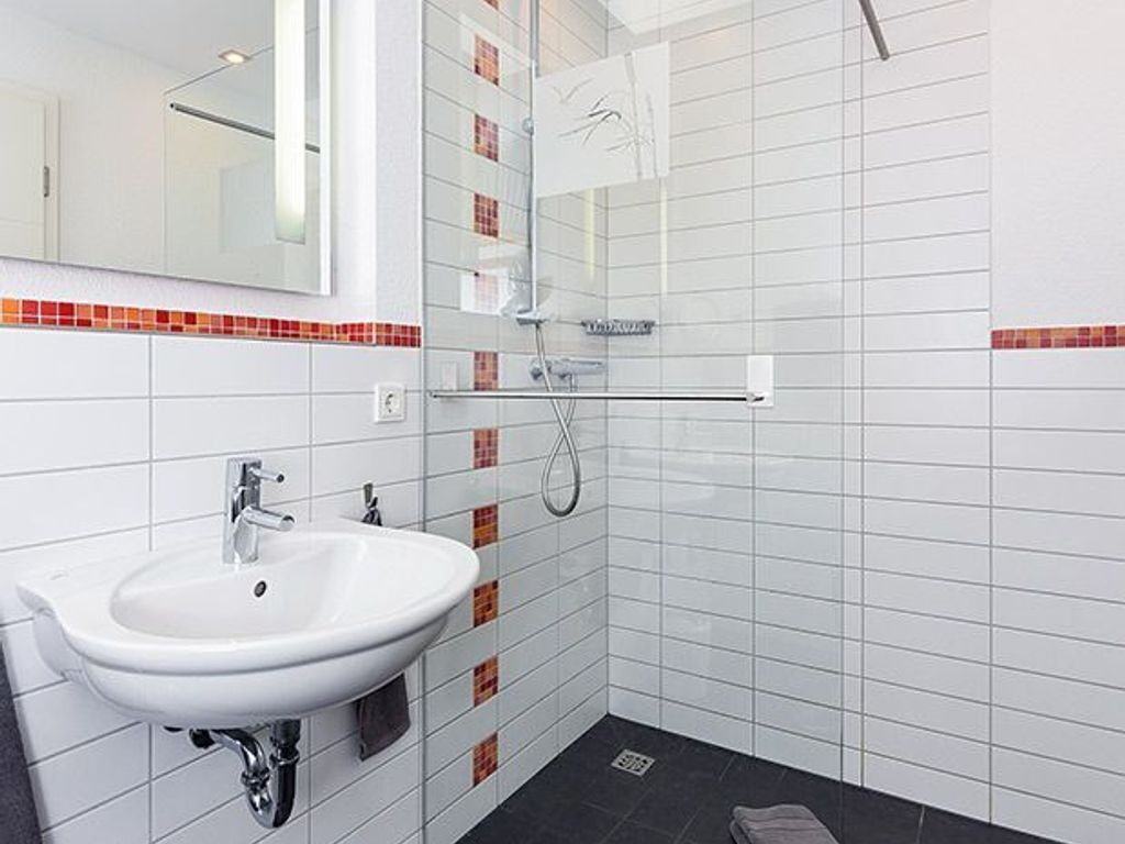 Un bagno con un lavandino bianco, uno specchio e una doccia.