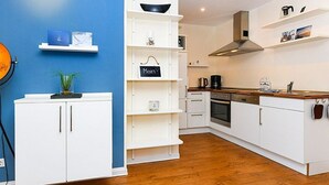 Eine moderne Küche mit weißen Schränken, einer blauen Akzentwand und Holzboden.