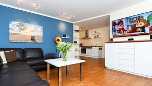 Ein modernes Wohnzimmer mit einer schwarzen Ledersofa, einem weißen Couchtisch und einem Bild von einer Strandlandschaft.