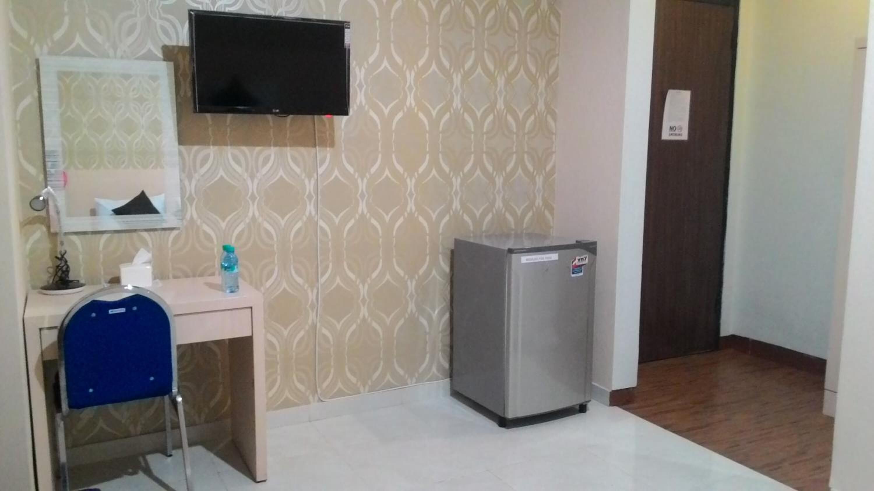 A small room with a desk, chair, and a refrigerator.