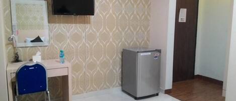 A small room with a desk, chair, and a refrigerator.