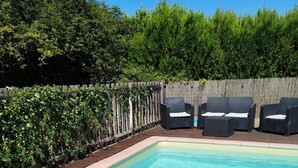 Une piscine dotée d’une terrasse en bois, entourée d’une clôture en bois et d’une végétation luxuriante.