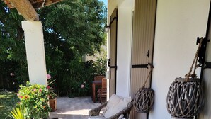 Un patio couvert aménagé avec des meubles en osier, une table décorée de bougies et des lanternes suspendues.
