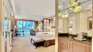 Habitación de hotel con cama, escritorio, silla y una ventana grande con vistas a la ciudad.