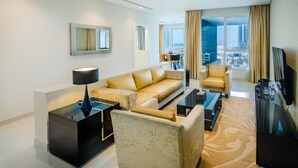 A modern hotel room with a sofa, armchair, and a TV. - OSKENA Vacation Homes - Damac Maison Canal View  (Dubai)