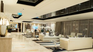 A spacious lobby with a high ceiling, modern furniture, and a large flat-screen TV. - OSKENA Vacation Homes - Damac Maison Canal View  (Dubai)