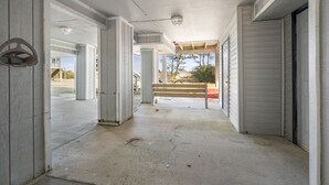 A covered outdoor area with concrete pillars, a bench, and a view of a building in the background.