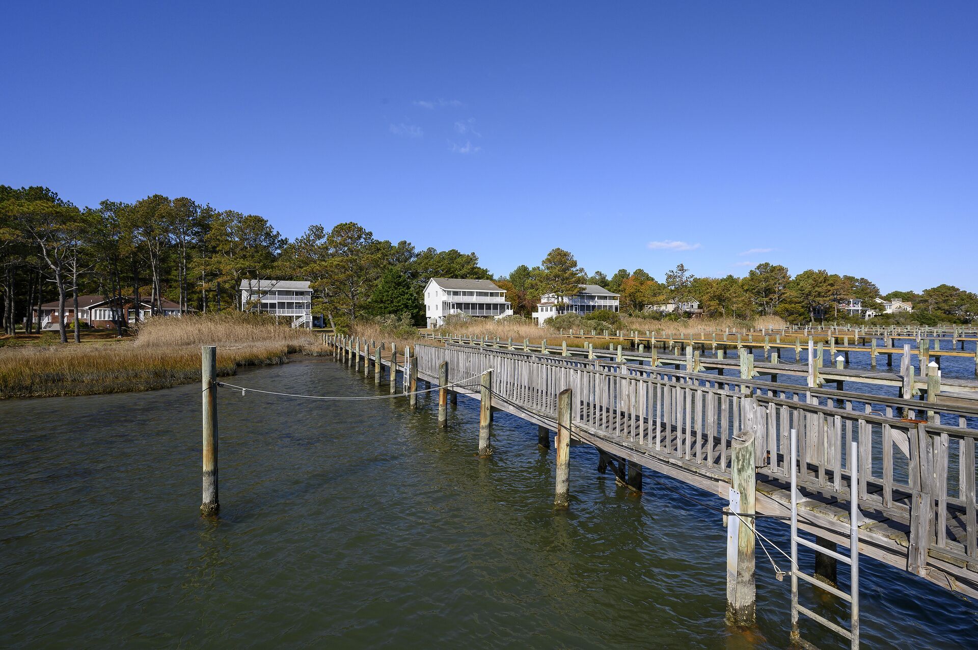 A wooden pier extending into a body of water, surrounded by residential buildings and trees.