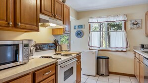 A compact kitchen with wooden cabinets, a microwave, stove, and a refrigerator.