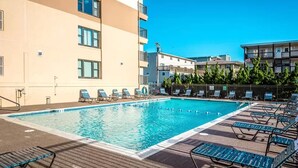 Une piscine avec des chaises longues et un bâtiment en arrière-plan.