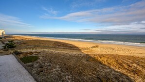 Un paysage côtier avec une plage de sable, une clôture en bois et un bâtiment en arrière-plan.