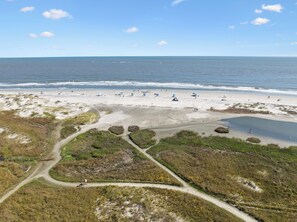 A beach with a clear sky, a sandy shore, and a few people.